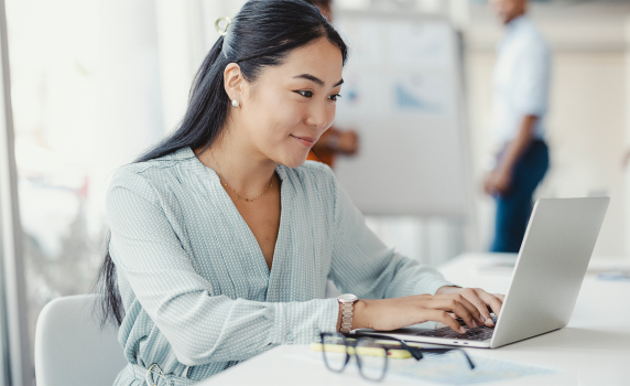 Picture of a woman smiling while typing on her laptop
