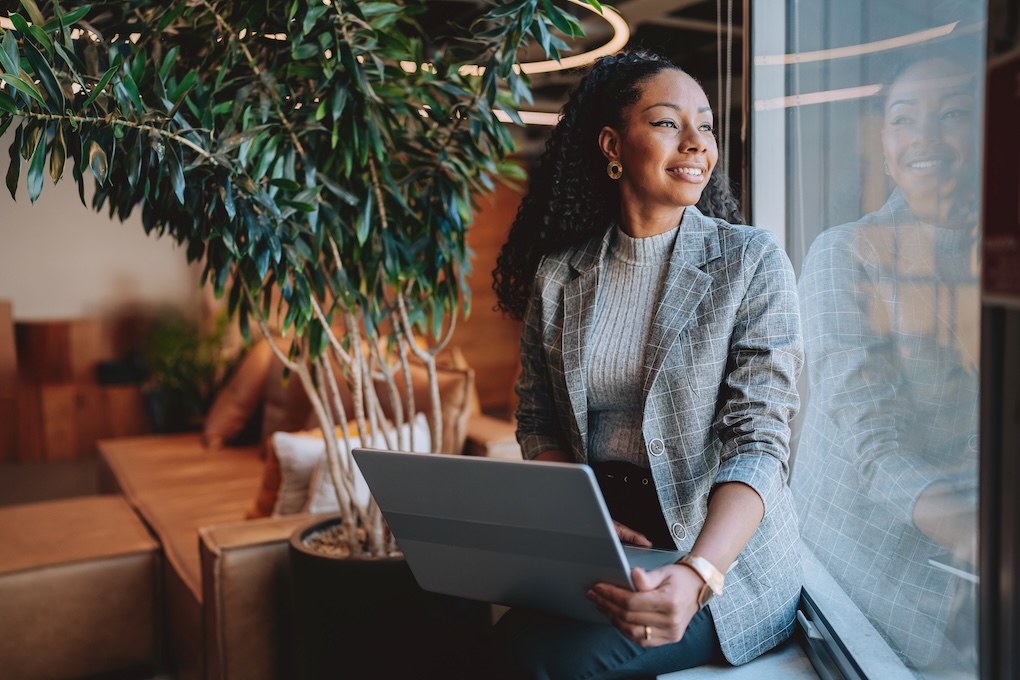 A smily woman with laptop looking by the window