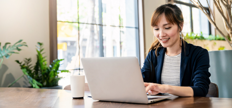 Picture of a woman smiling at her laptop.