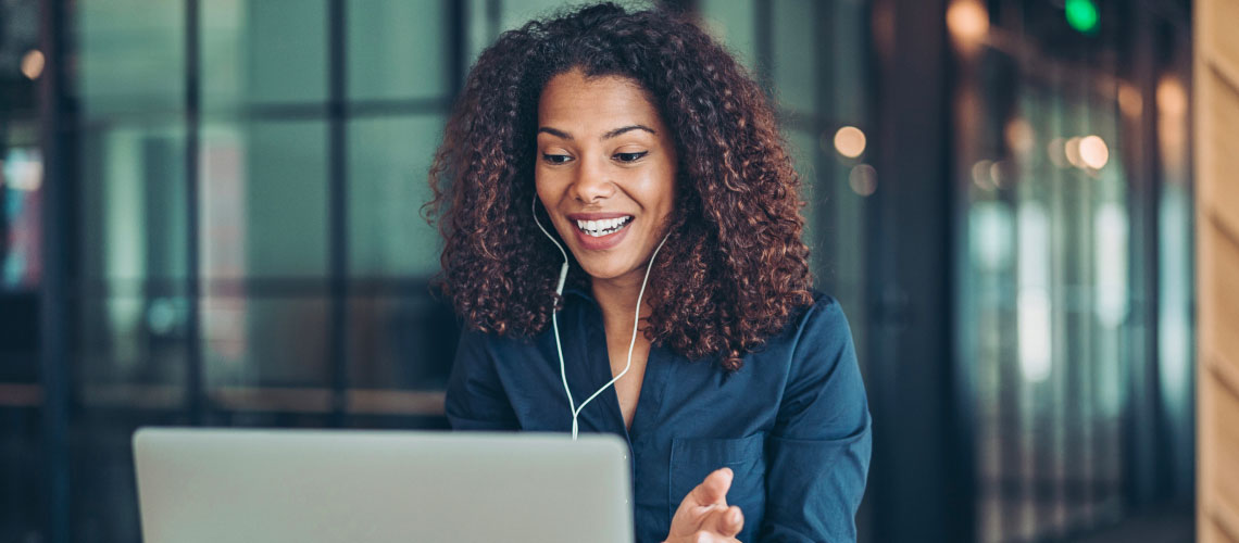 Photo of a woman wearing earphones while speaking on a virtual meeting 